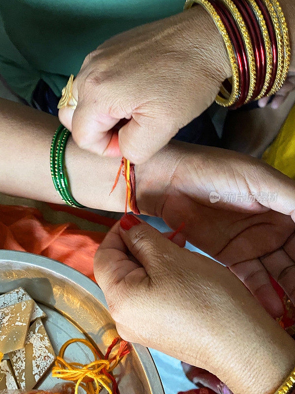 特写图片，无法辨认的印度，印度妇女在她哥哥的手腕上系rakhi(绳手镯)，Raksha Bandhan印度教节日的兄弟和爱，上升的观点